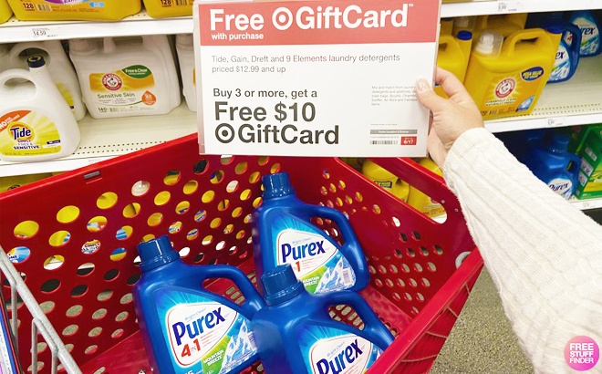 Three Purex Liquid Laundry Detergents in Target shopping cart with a hand holding a sign for a giftcard offer abive them 2