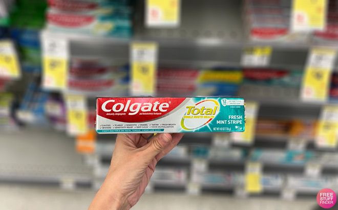 A Person Holding a Colgate Toothpaste Fresh Mint Stripe in an Aisle at Walgreens